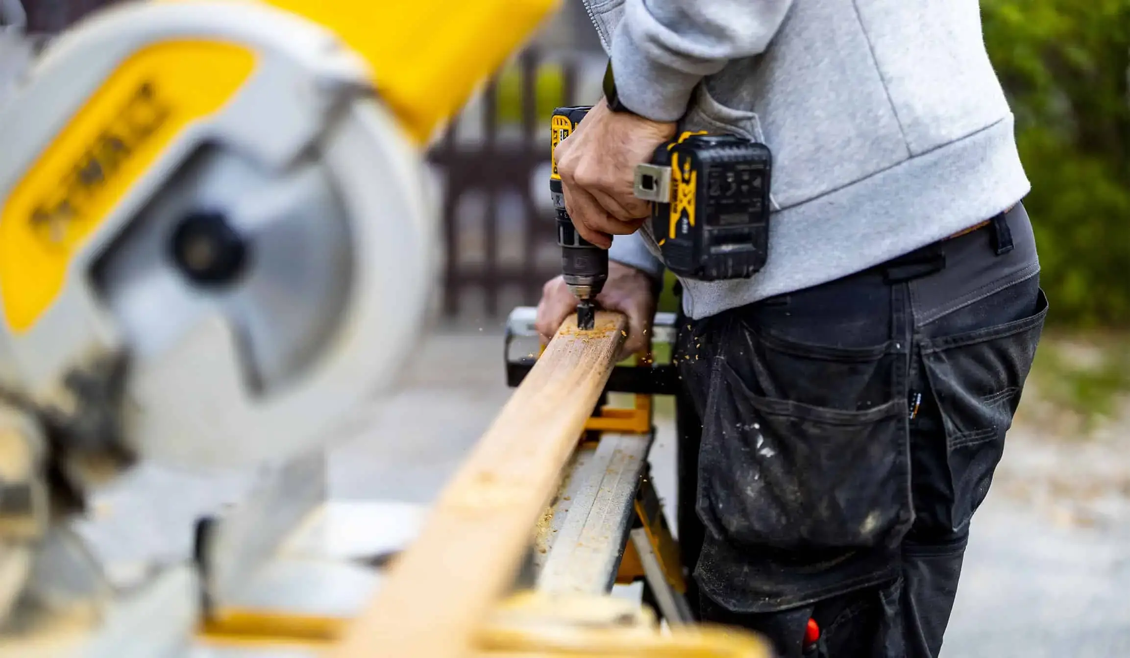 Tømrer arbejder med træmaterialer på byggepladsen med værktøj.