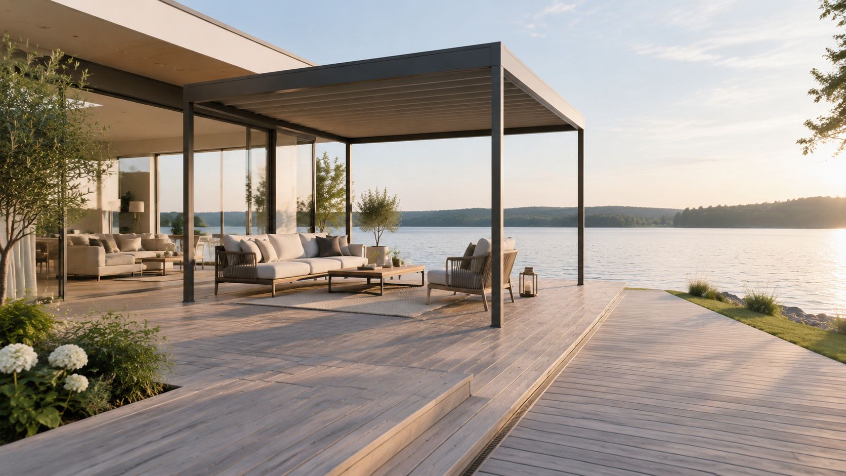 En moderne terrasse ved vandet med elegant udendørsmøbelarrangement og en overdækket pergola i solnedgangens lys.